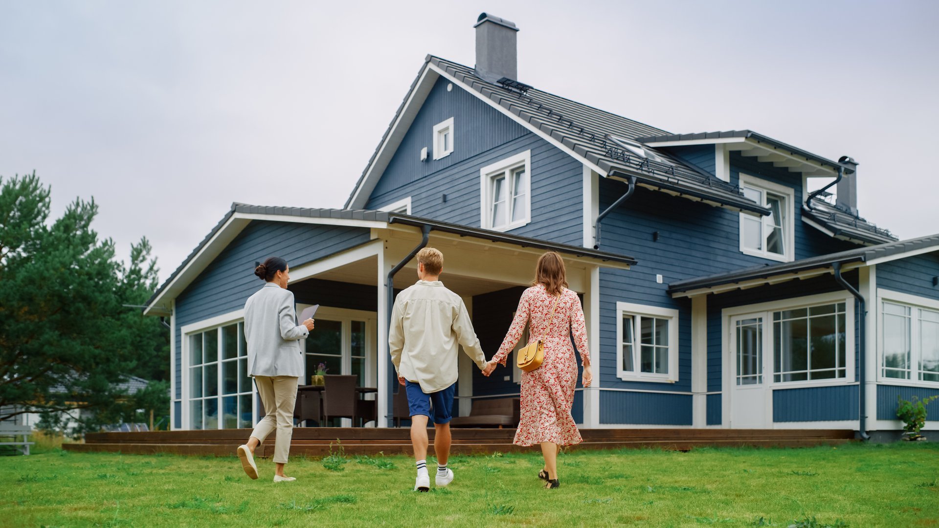 Young couple viewing a property for sale while talking with a real estate agent outside the house