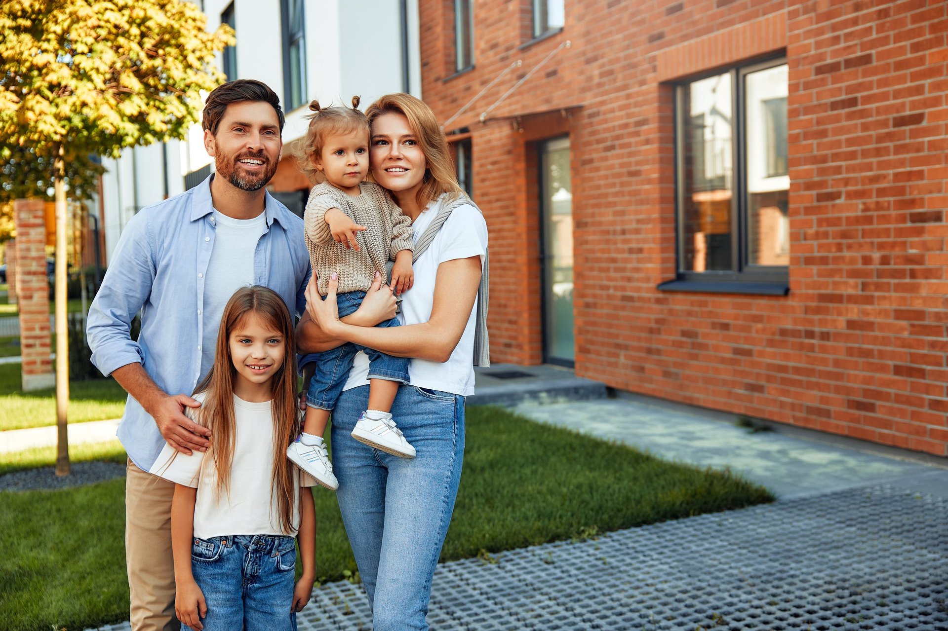 Family standing in front of their newly purchased home, representing student owner-occupancy