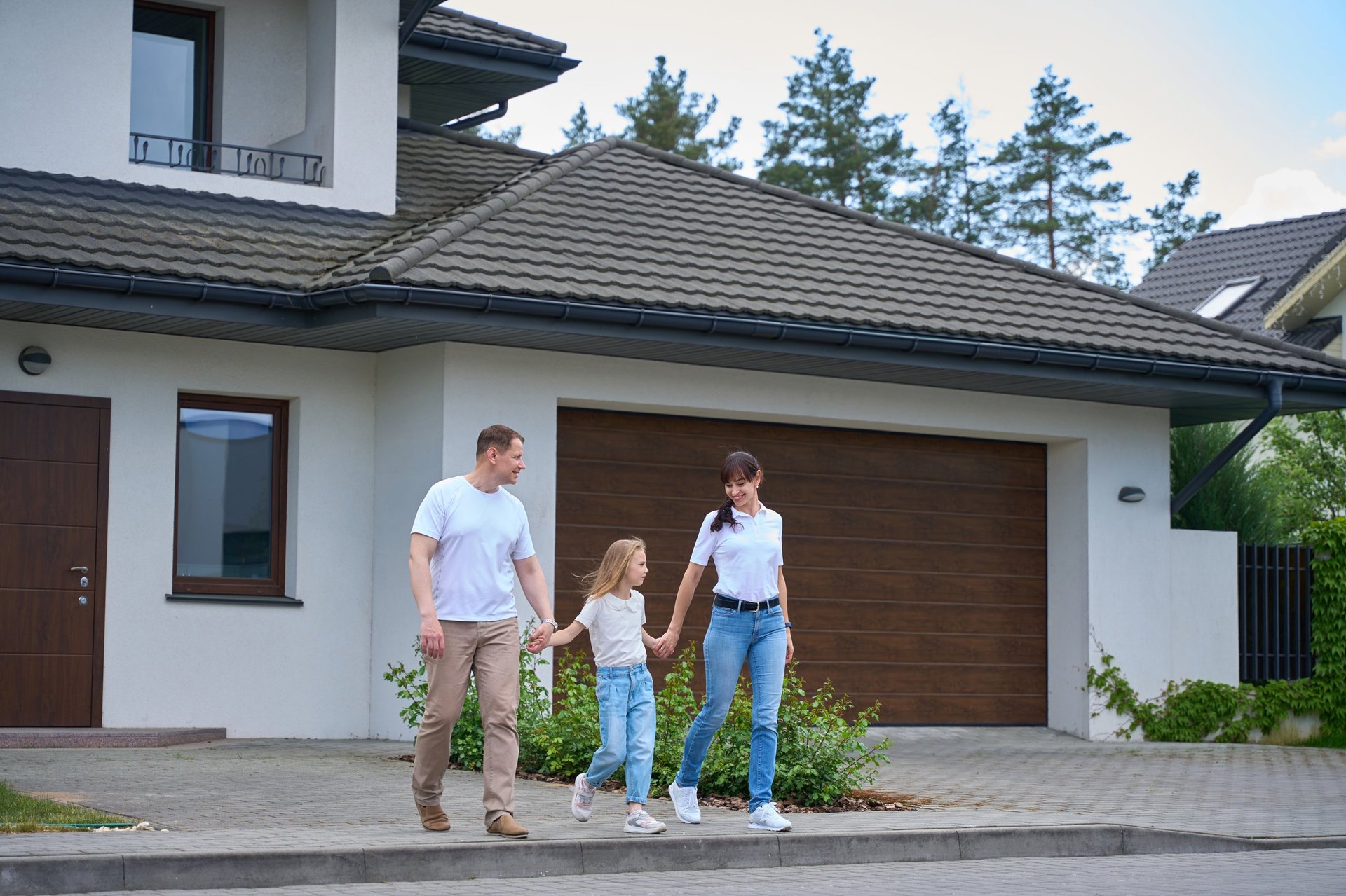 Parents and their college-aged daughter leaving a modern townhouse outdoors on a sunny day