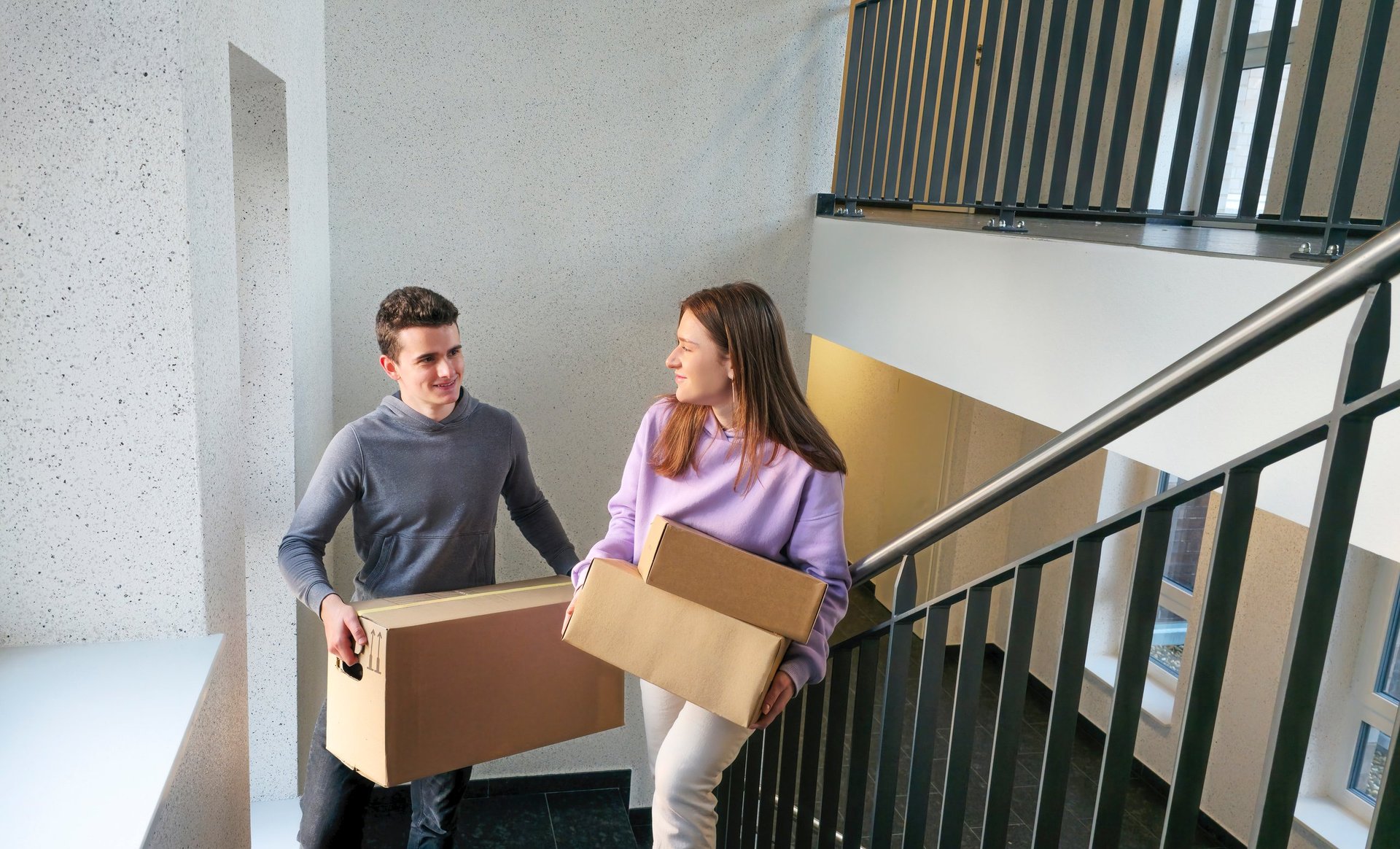 College students carrying moving boxes into a residential home, not a dorm