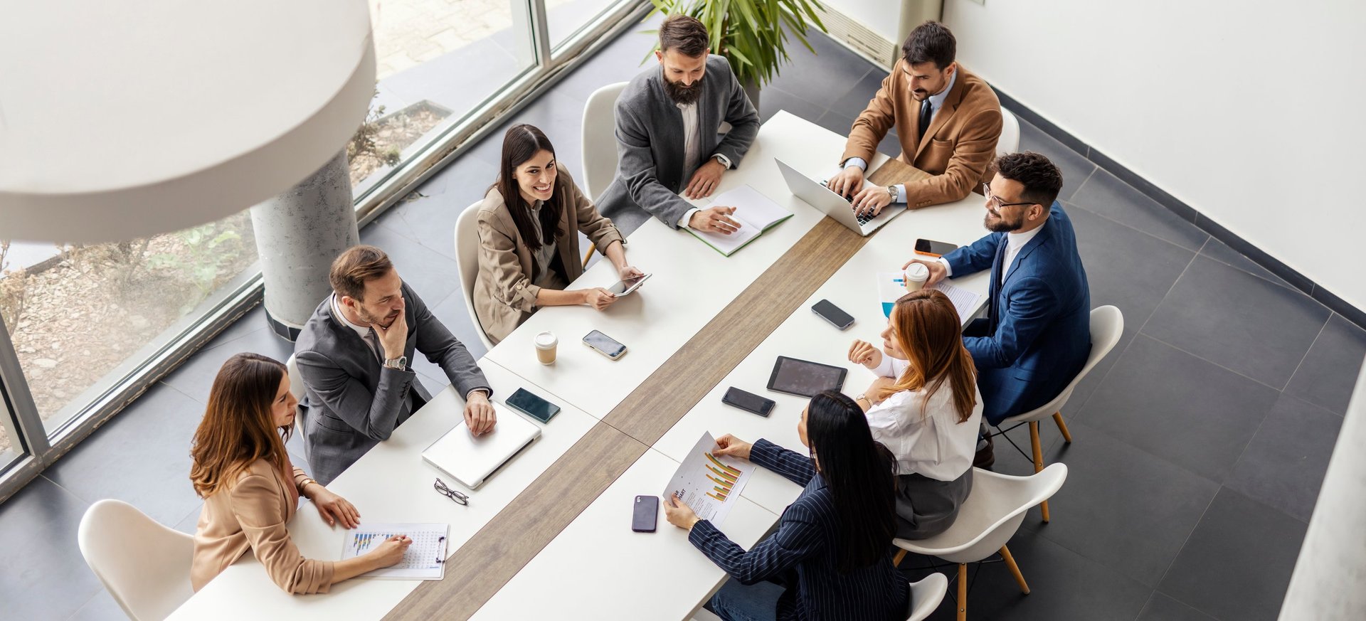 From above view of leadership team sitting at conference table at boardroom and having meeting