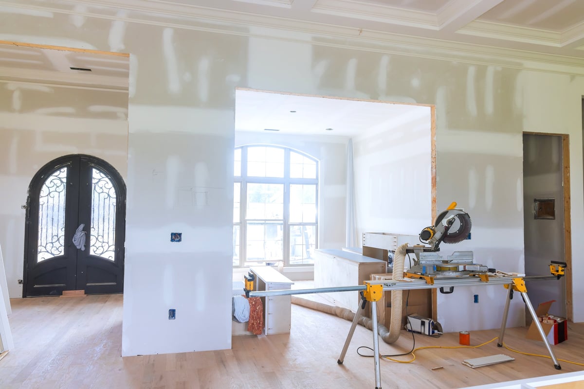 Fix and flip investor preparing a modern living space during a home renovation with unfinished walls and tools