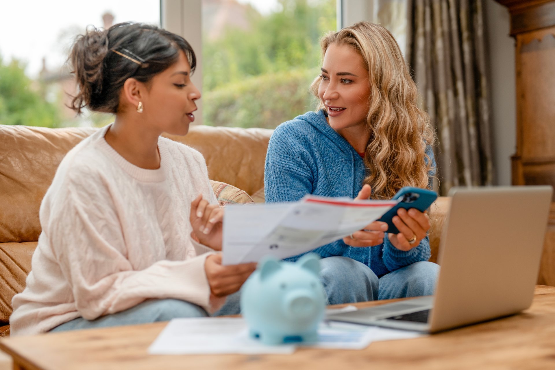 Parent and young adult reviewing financial documents together in a comfortable living room