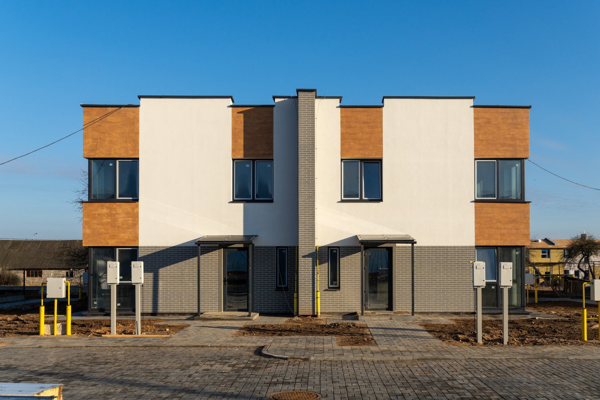 Modern two-story townhouse exterior in a suburban neighborhood under a clear blue sky
